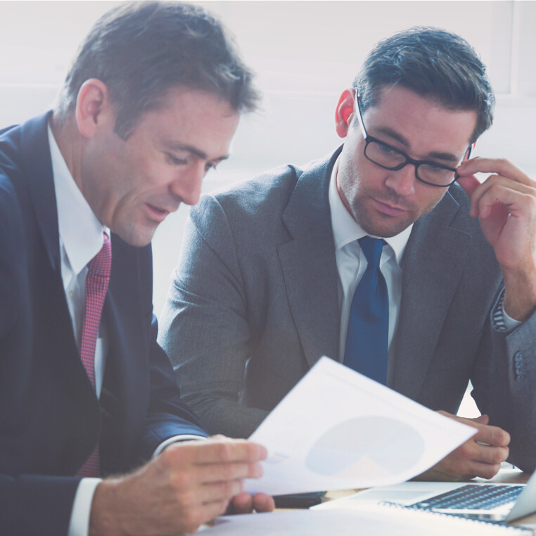 two business men looking at a graph on a piece of paper