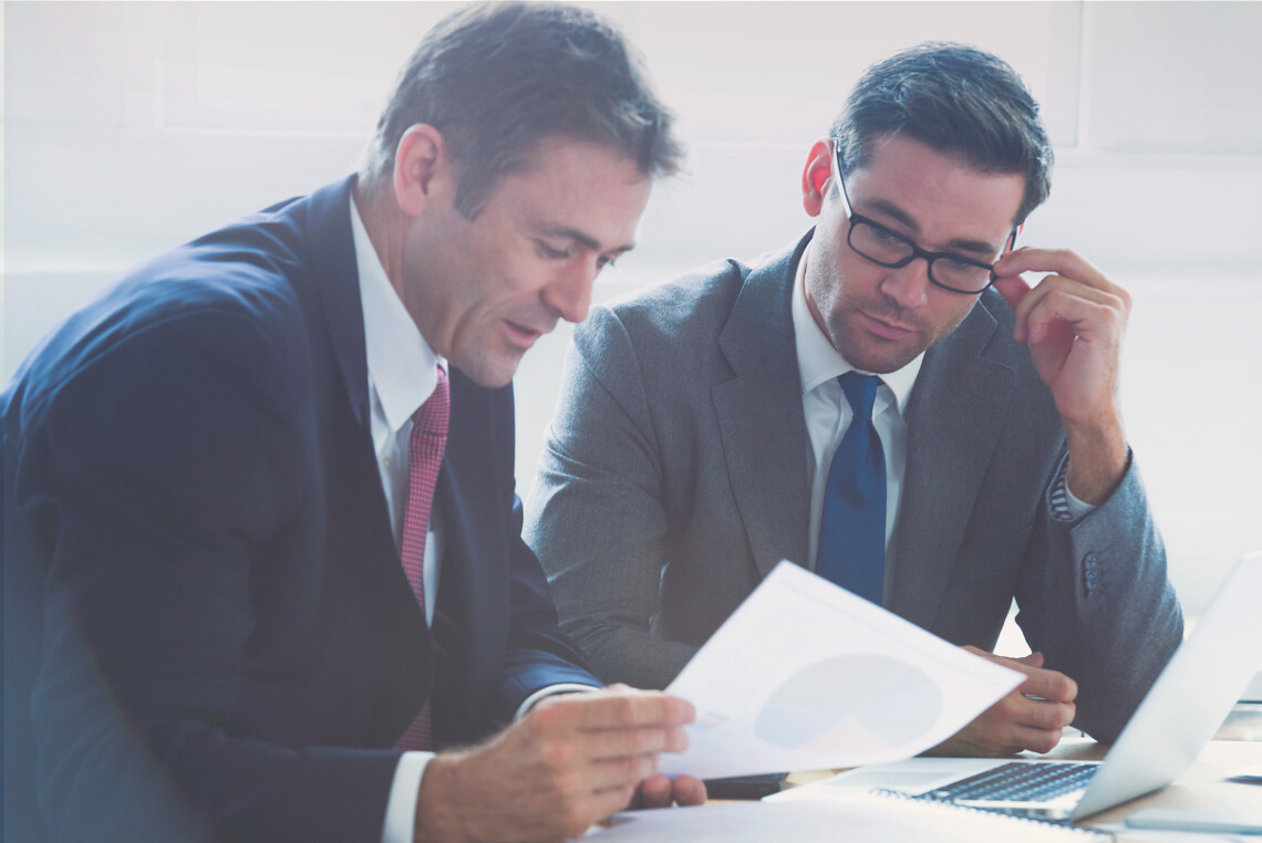 two business men looking at a graph on a piece of paper